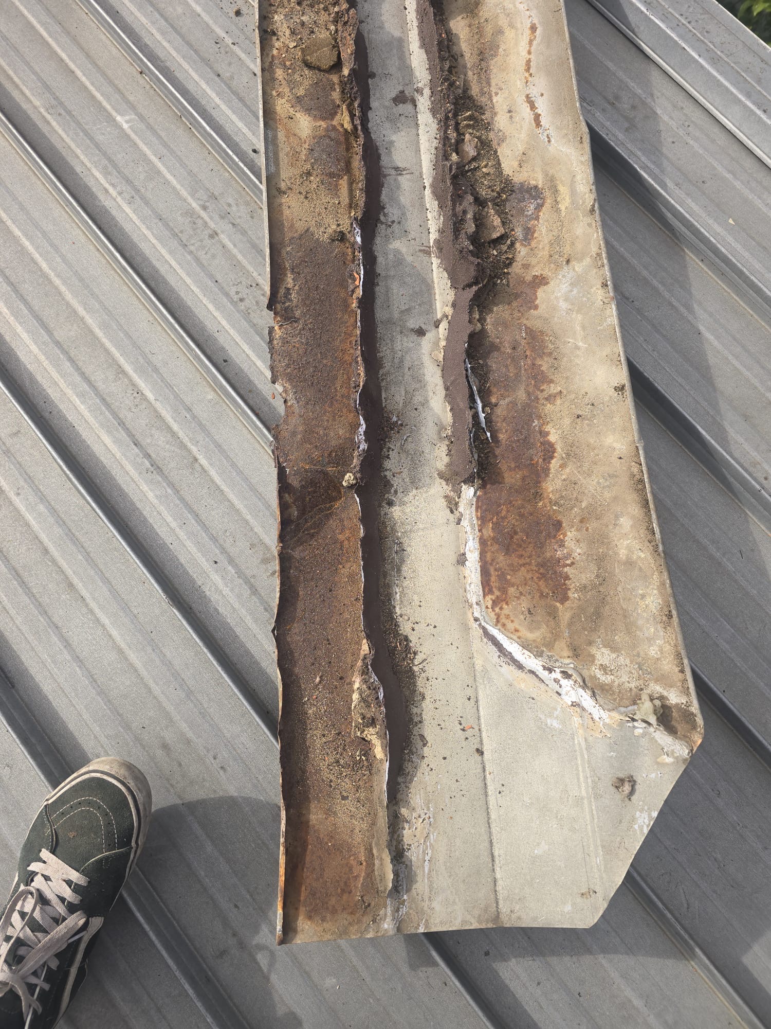 Removed metal valley showing heavy rust and deterioration along the mortar contact areas