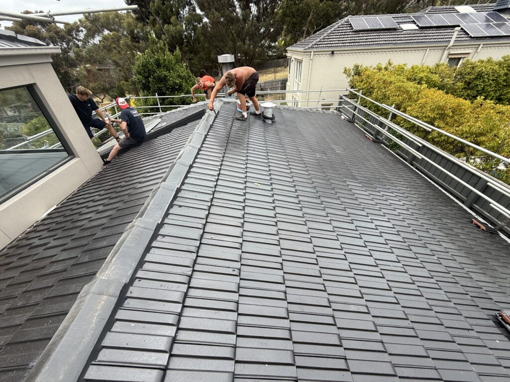 Roofing team working on ridge capping on a grey tiled roof