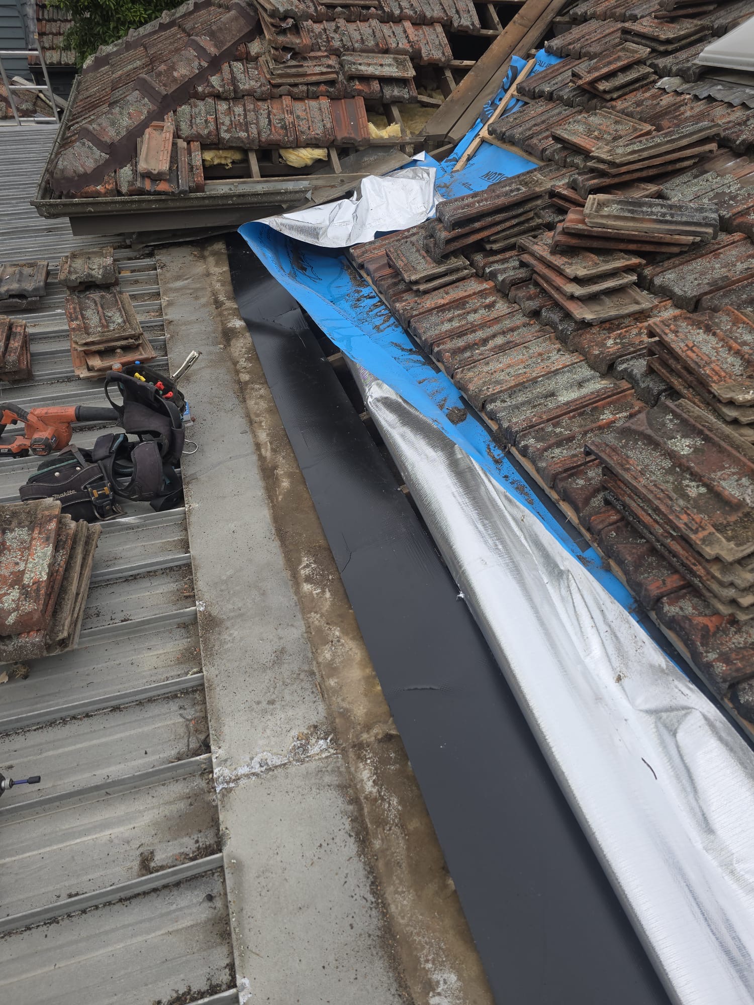 New blue roof sarking and weatherproofing work at the lower tiled roof junction