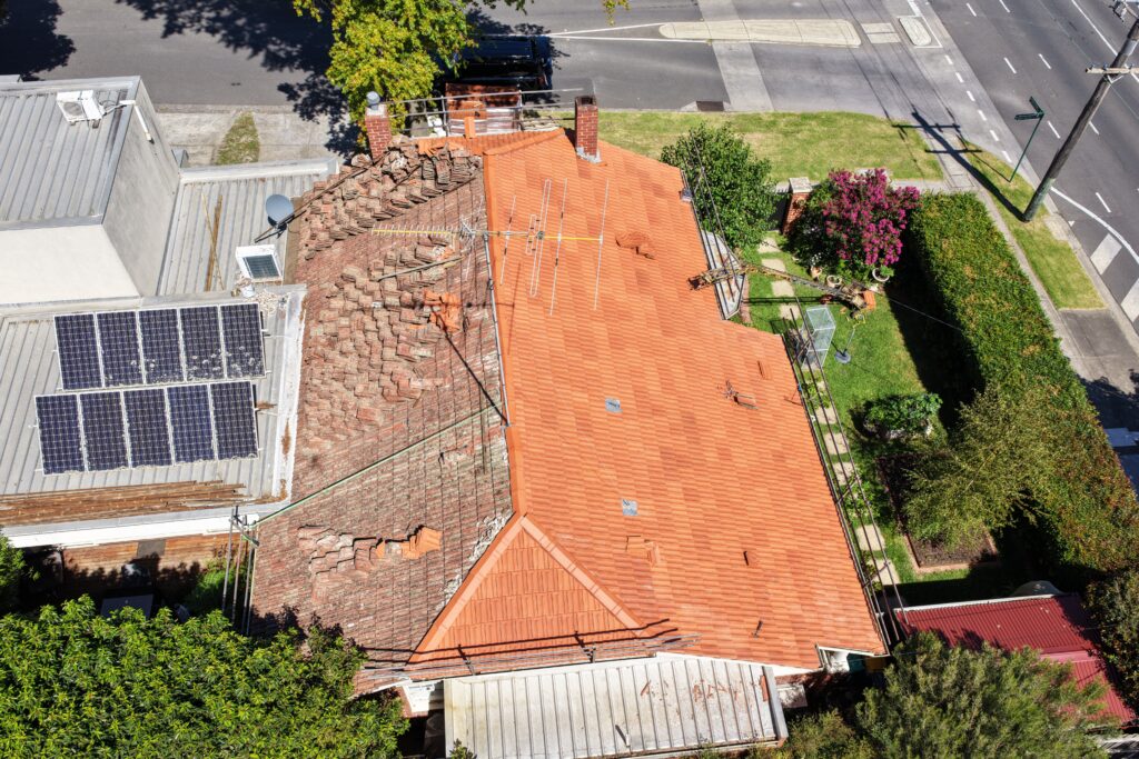 Terracotta roof replacement in progress showing new orange tiles beside the old roof
