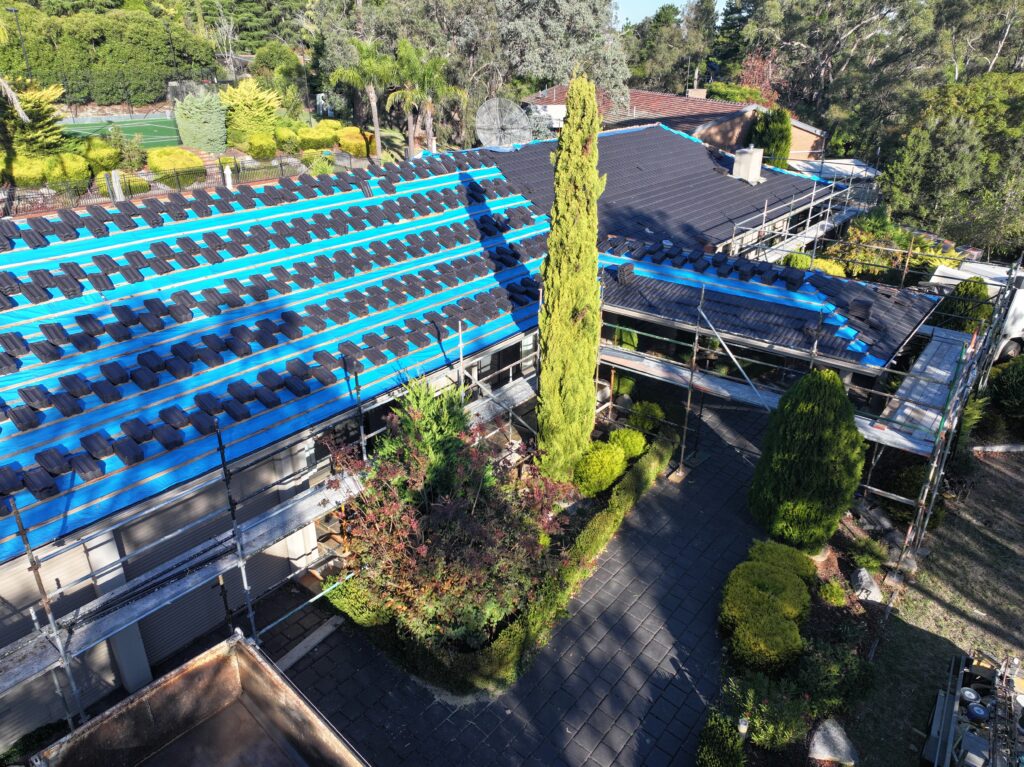 Tile roof replacement in progress with blue sarking, timber battens and stacked roof tiles