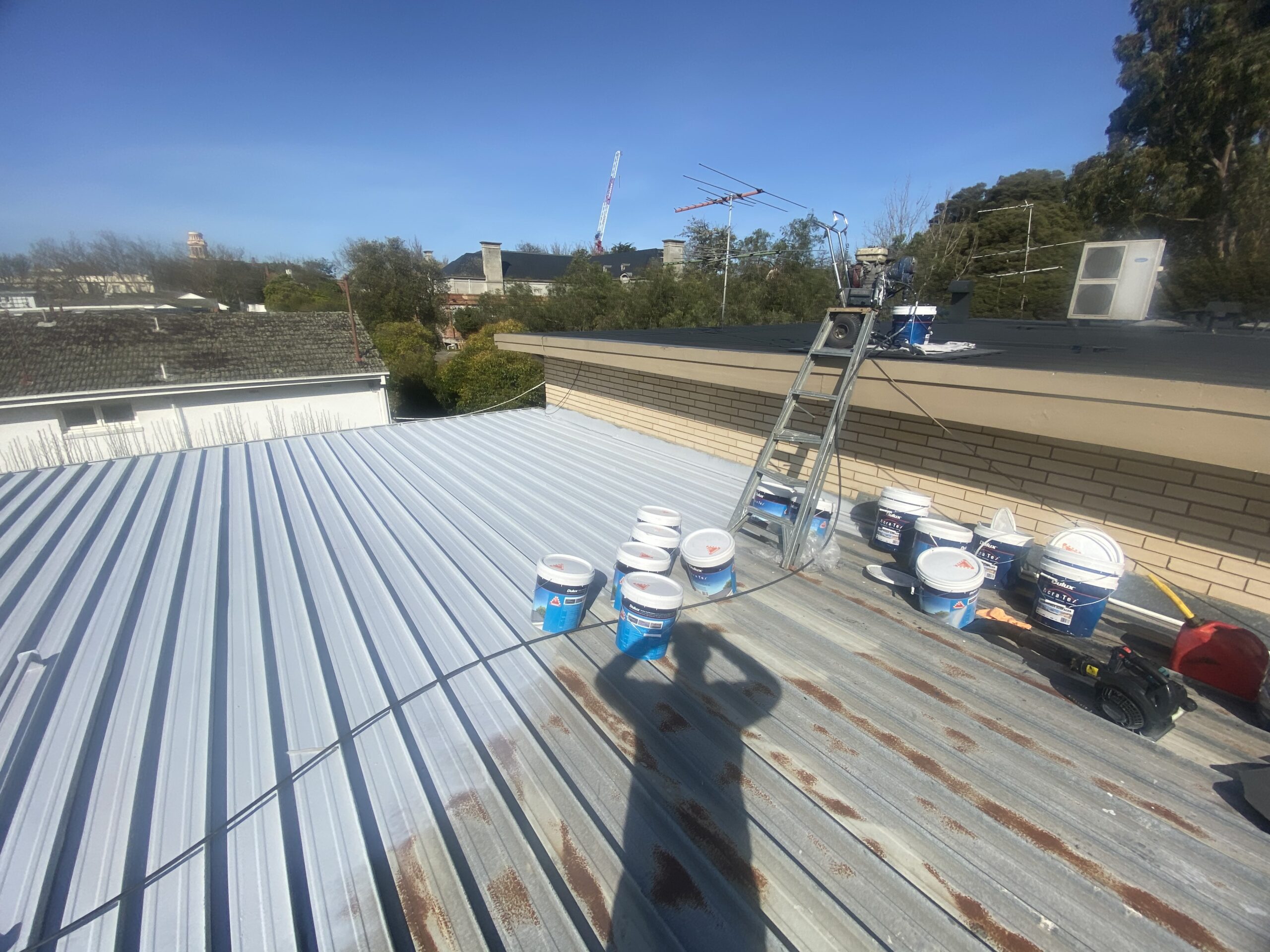Light-coloured coating beside exposed weathered metal roofing