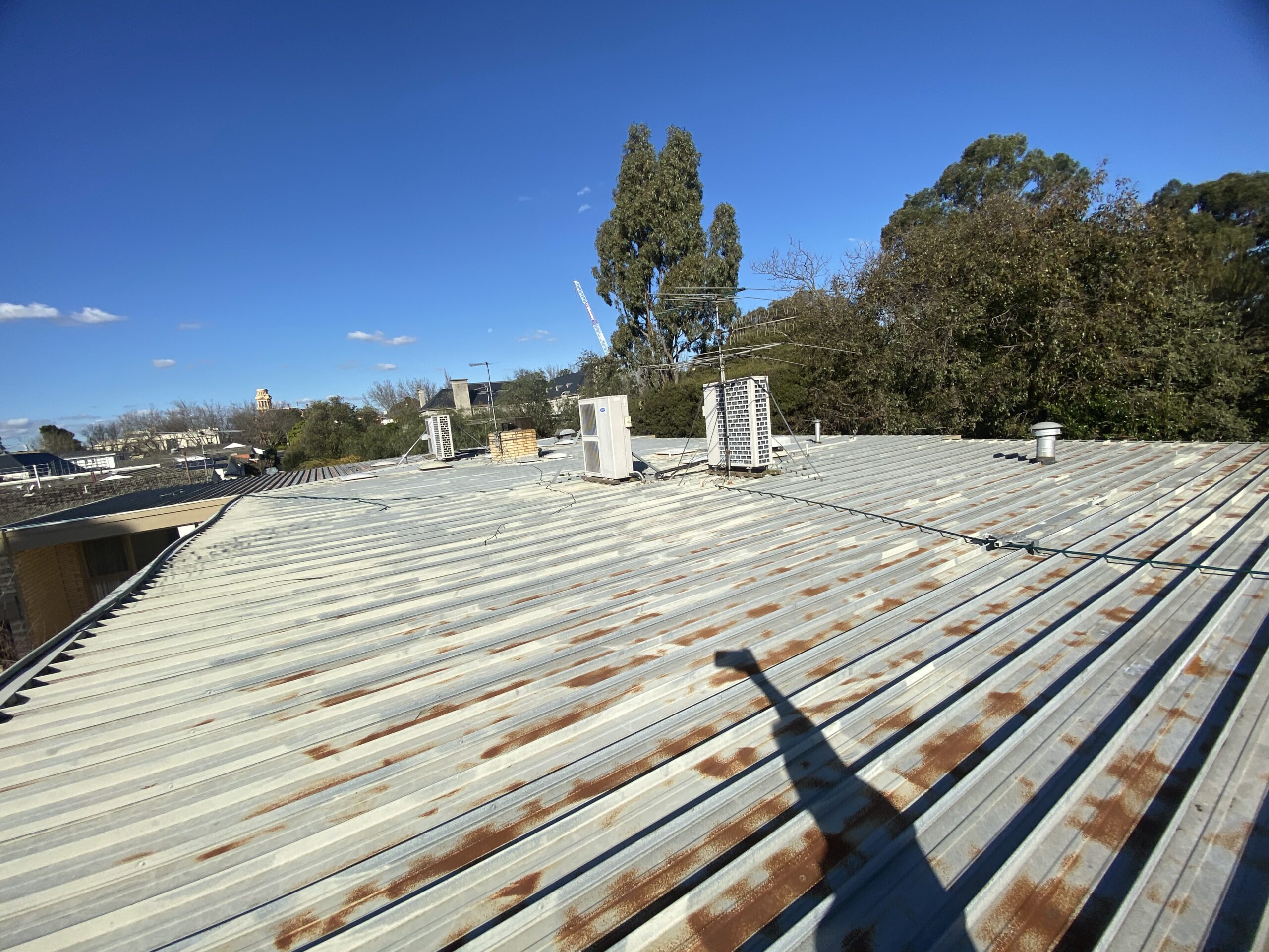 Rust-coloured patches across weathered metal roof sheeting before restoration