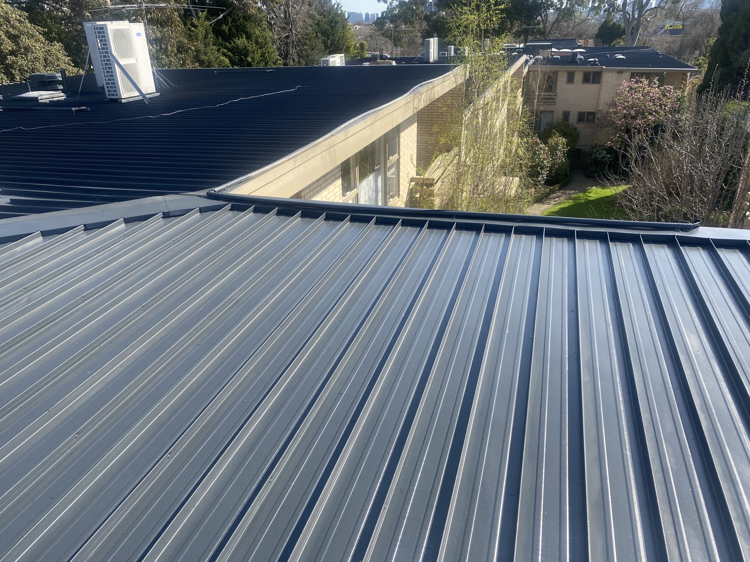 Dark-grey restored metal roof showing the raised profiles and roof edge